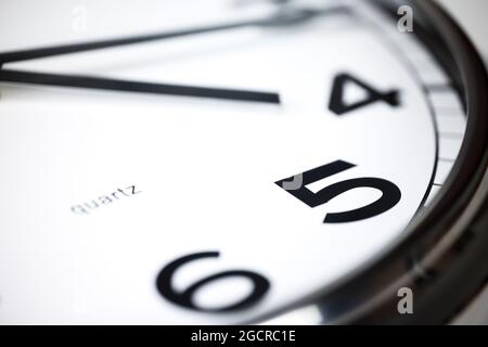 Un moderno orologio da parete bianco con struttura in alluminio. Vicino a un orologio a parete, i puntatori a metà passo 4. Messa a fuoco selettiva sul numero 5 o 5 ore. R Foto Stock