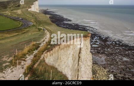 Eastbourne, East Sussex, Regno Unito. 10 agosto 2021. Ulteriori precipitazioni sembrano imminenti dopo che le precipitazioni espianti stanno ammorbidendo il gesso ad alta porosità. Fessure di estensione non visibili sulla parte superiore a causa della copertura foraggio. Questa foto a 100 metri a est della più recente grande caduta vicino alla Belle Tout, Beachy Head faro in lontananza, mostra una massiccia colonna ancora appesa. Credit: David Burr/Alamy Live News Foto Stock