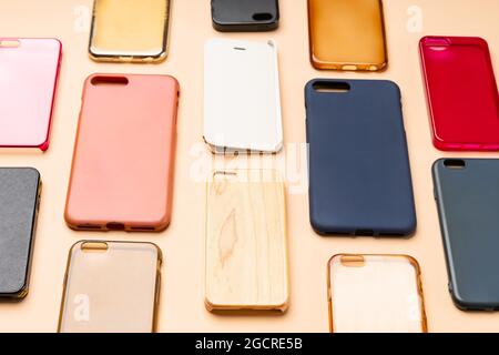 Pila di coprischiera in plastica multicolore per telefono cellulare. Scelta di accessori di protezione per smartphone su sfondo neutro. Un sacco di telefono in silicone Foto Stock