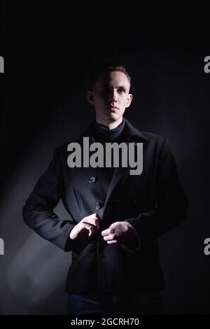Uomo elegante in camice nero in studio scuro Foto Stock