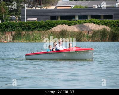 Berlare, Belgio, 22 luglio 2021, Man in un cappello salpa con la sua famiglia, moglie e due bambini in una barca elettrica su un lago Foto Stock