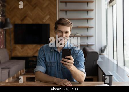 Felice gioioso ragazzo millenario bello scattare foto su smartphone Foto Stock