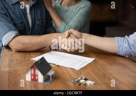 Coppia di clienti e broker immobiliare che dà handshakes Foto Stock