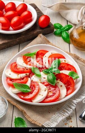 Insalata caprese italiana con pomodori a fette, mozzarella e basilico su sfondo beige. Foto Stock