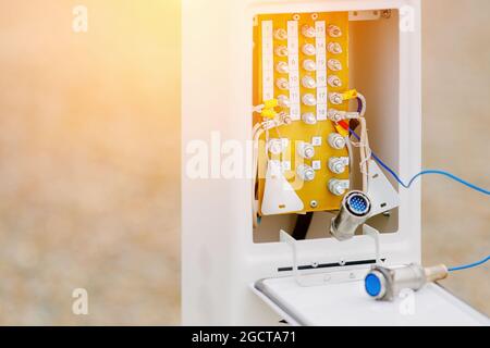 Aprire la schermatura con i fili del dispositivo di controllo e misurazione presso lo stabilimento di produzione. Regolazione e diagnostica dell'attrezzatura. Il tema dell'elettricità. Sfondo. Foto Stock