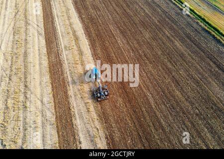Il trattore aratura il terreno su un terreno coltivato. Vista aerea del trattore preparazione del terreno per la piantagione di prodotti Foto Stock