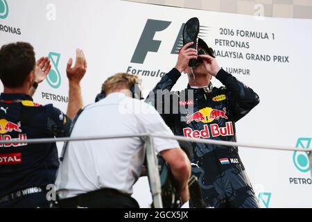 Secondo classificato Max Verstappen (NLD) Red Bull Racing festeggia sul podio bevendo champagne dal boot da gara del vincitore Daniel Ricciardo (AUS) Red Bull Racing. Gran Premio della Malesia, sabato 2 ottobre 2016. Sepang, Kuala Lumpur, Malesia. Foto Stock