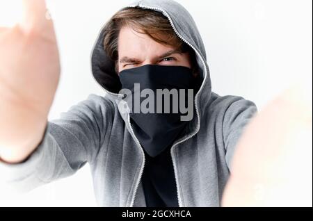 uomo che nasconde il suo volto sotto una maschera con un cappuccio anonimato crimine furto primo piano Foto Stock