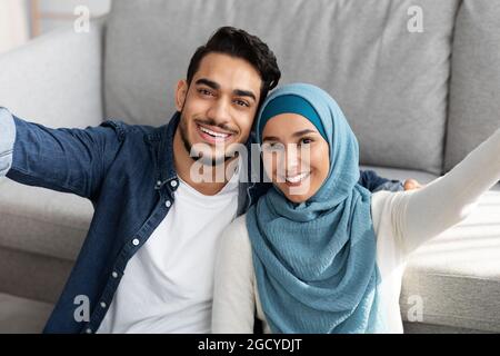 Positivo famiglia medio-orientale che prende selfie in nuovo appartamento Foto Stock