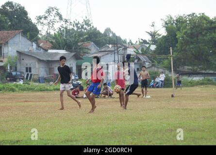 GIACARTA, INDONESIA - 09 agosto 2021: Alcuni ragazzi giocano a calcio sul campo senza indossare scarpe Foto Stock