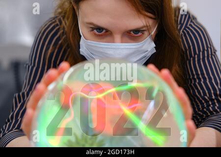 Previsioni e fortune-telling sul coronavirus su una sfera magica di cristallo in 2022. Il problema con l'epidemia di covidio e la vaccinazione contro il virus Foto Stock