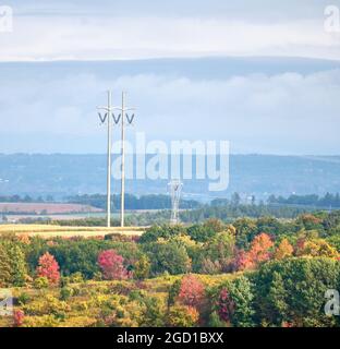 Un pilone ad alta tensione e una più piccola torre di cugini sull'autunno paesaggistico nella città di Florida, NY Foto Stock