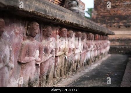 Una fila di buddhas (o solo monaci biddhisti), scolpiti sulla base di un antico palazzo Foto Stock