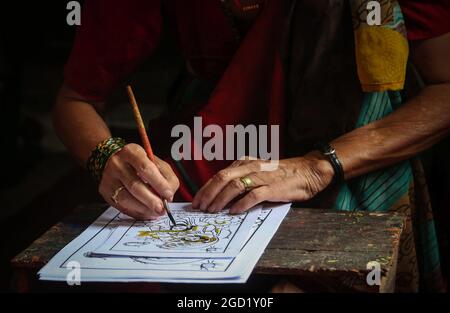 Bhaktapur, Bagmati, Nepal. 10 agosto 2021. Chet Kumari Chitrakar, 68, popolarissimo conosciuto come ''creatore degli dei'', dà il tocco finale all'immagine tradizionale per il festival di Nag Panchami, un festival indù per adorare la divinità serpente a Bhaktapur, una città conosciuta anche come ''˜la città dei devoti' in Nepal il 10 agosto 2021. Chet Kumari Chitrakar e la famiglia continuano a fare tali immagini di stampa a mano per molti festival, nonostante la minore domanda a causa dell'interesse della gente nelle moderne immagini di stampa a macchina. Le famiglie di Chitrakar sono conosciute basicamente come pittori e scultori in Nepal che hanno rappresentato gli dei e g Foto Stock