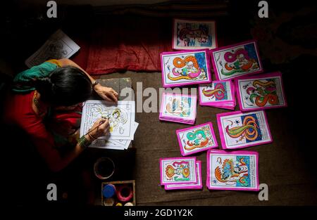 Bhaktapur, Bagmati, Nepal. 10 agosto 2021. Chet Kumari Chitrakar, 68, popolarissimo conosciuto come ''creatore degli dei'', prepara l'immagine tradizionale per il prossimo festival Nag Panchami, un festival indù per adorare la divinità serpente a Bhaktapur, una città conosciuta anche come ''˜la città dei devoti' in Nepal il 10 agosto 2021. Chet Kumari Chitrakar e la famiglia continuano a fare tali immagini di stampa a mano per molti festival, nonostante la minore domanda a causa dell'interesse della gente nelle moderne immagini di stampa a macchina. Le famiglie di Chitrakar sono conosciute basicamente come pittori e scultori in Nepal che hanno rappresentato gli dei e le dea in Foto Stock