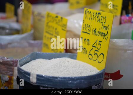 Mercato notturno in Thailandia: Un sacco pieno di vari tipi di riso sono accatastati su un pavimento al mercato di strada a Bangkok Foto Stock