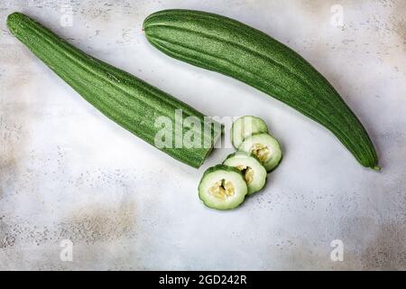 Cetriolo armeno a righe (Cucumis melo var. Flexuosus) in cima a uno sfondo grigio in cemento, vista dall'alto, spazio copia Foto Stock