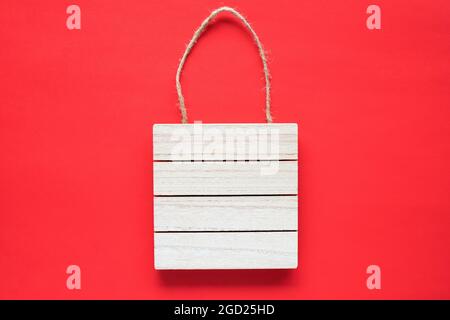 Telaio cartello in legno appeso su una corda su sfondo rosso. Concetto di vendita per le vacanze con spazio per la copia Foto Stock