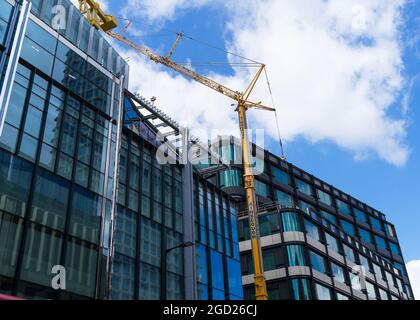 Costruzione di nuovi edifici su Charing Cross Road con una gru gialla tra le strutture. Londra - 10 agosto 2021 Foto Stock