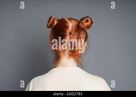 vista posteriore della donna dai capelli rossi con ciambelle spaziali Foto Stock