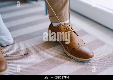 L'uomo sta stringendo i lacci sulle brogues marroni. Primo piano Foto Stock