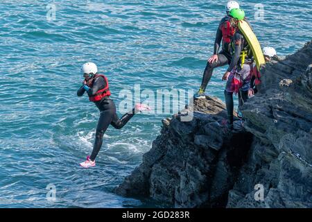 I vacanzieri saltano dalle rocce costellando con una guida su Towan Head a Newquay in Cornovaglia. Foto Stock