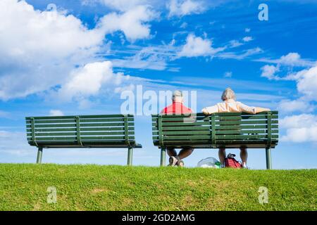 Vista posteriore della coppia anziana seduta sul sedile che si affaccia sul mare in una giornata di sole. Foto Stock