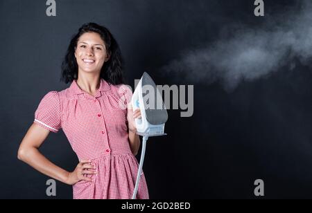 Ferro da stiro per voi. pinup ragazza preparare la stiratura. vintage signora tenere ferro moderno. Vita quotidiana e casalinghi. Donna retrò con ferro. Cameriera allegra Foto Stock