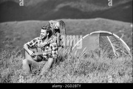 Aria fresca e sensazioni pure. Coppia in amore felice rilassante sfondo natura. Fidanzata chitarra vicino tenda campeggio. Vacanze estive. Campeggio Foto Stock