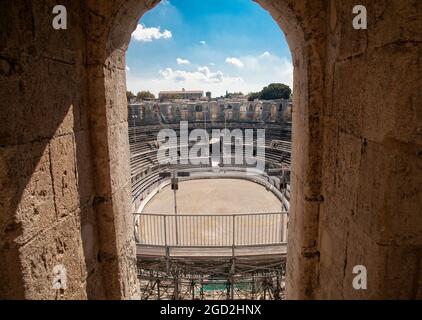 Sbirciando attraverso uno dei numerosi archi in pietra dell'Arena romana di Arles, Francia. Foto Stock