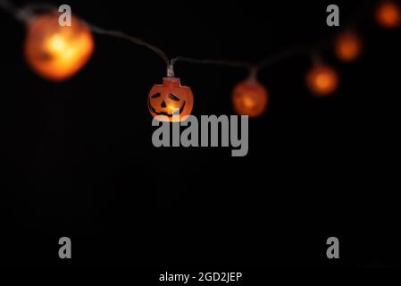 Garland di luci sotto forma di una zucca su uno sfondo nero, concetto di Halloween, decorazione per la festa, spazio di copia. Foto Stock