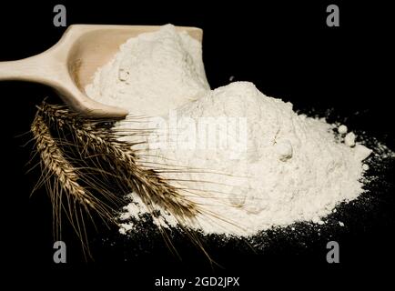 Farina. Sessola con farina e orecchie di grano da vicino su fondo nero Foto Stock