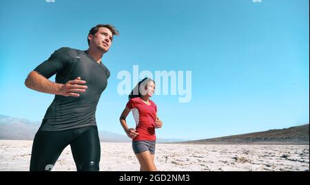 Allenamento di resistenza degli atleti in ambienti esterni a temperature estreme, che corrono nel banner estivo del deserto. Donna e uomo runner all'aperto. Foto Stock