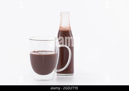 Tazza di vetro dall'aspetto delizioso e bottiglia di frullato di cioccolato: Messa a fuoco selettiva e primo piano Foto Stock