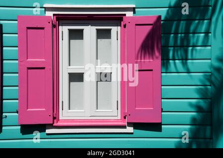 Vibrante edificio e finestra color turchese caraibico con persiane rosa Foto Stock