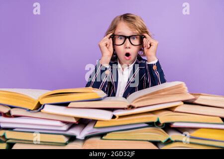 Ritratto di attraente divertente stupito ragazzo lettura stack libro di lettura Pout labbra isolato su viola sfondo colore Foto Stock