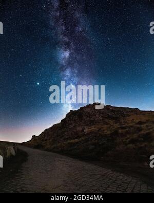 Astronomia Foto scattata a Serra da Freita. Con via Láctea che appare dietro una collina e una strada di campagna. Foto Stock
