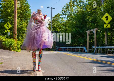 Woodstock, NY, USA - 8 agosto 2021: Un manichino femminile dipinto in un design psichedelico e vestito con un abito in mesh viola, si erge su una strada per attrarre pa Foto Stock