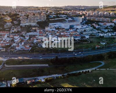 Vista di un piccolo quartiere lungo una strada trafficata al tramonto, Cruz Quebrada-Dafundo, Lisbona, Portogallo Foto Stock