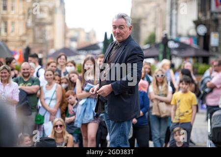 Edimburgo, Scozia, Regno Unito. 10 agosto 2021. NELLA FOTO: Un artista di strada si esibisce ad una folla impazzita di persone . Scene del Royal Mile durante il Fringe Festival di Edimburgo, che vede una folla impoverita di persone che visitano la città e una piccola quantità di artisti di strada e attori che ancora intrattiene i passanti. Credit: Colin Fisher/Alamy Live News Foto Stock