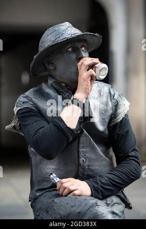 Edimburgo, Scozia, Regno Unito. 10 agosto 2021. NELLA FOTO: Una statua in movimento atto, visto prendere una pausa. Scene del Royal Mile durante il Fringe Festival di Edimburgo, che vede una folla impoverita di persone che visitano la città e una piccola quantità di artisti di strada e attori che ancora intrattiene i passanti. Credit: Colin Fisher/Alamy Live News Foto Stock