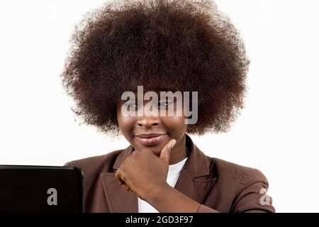 Giovane donna nera Ispanica dirigente d'affari latino, con capelli afro, con gesto di interesse guardando un computer portatile, su sfondo bianco Foto Stock