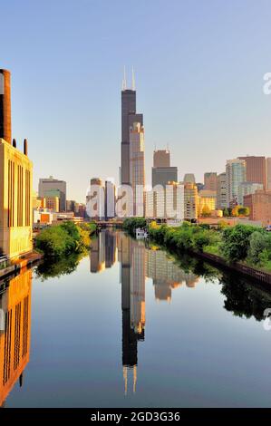 Chicago, Illinois, USA. Il sole della mattina presto illumina una parte dello skyline del South Loop di Chicago che si riflette nel South Branch del fiume Chicago. Foto Stock