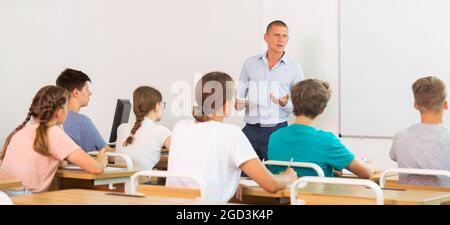 Insegnante che spiega il materiale di studio agli adolescenti durante la lezione Foto Stock