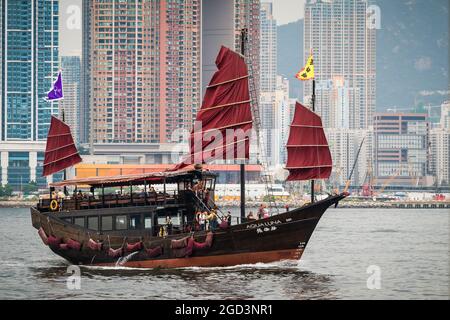 L'Aqua Luna, una giunca cinese costruita nel 2006, passa davanti agli alti blocchi di appartamenti di Union Square a West Kowloon mentre naviga nel Victoria Harbour Foto Stock