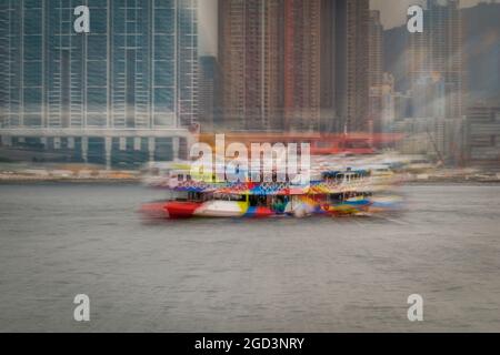 Trattamento di sfocatura zoom della 'Night Star', una delle flotte Star Ferry, passando per gli alti blocchi di appartamenti di Union Square, West Kowloon Foto Stock