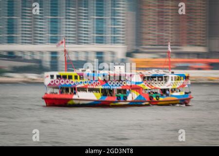 Trattamento di sfocatura del movimento della 'Night Star', una delle flotte Star Ferry, passando per gli alti blocchi di appartamenti di Union Square, West Kowloon Foto Stock