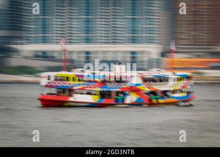 Trattamento di sfocatura del movimento della 'Night Star', una delle flotte Star Ferry, passando per gli alti blocchi di appartamenti di Union Square, West Kowloon Foto Stock