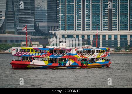 La 'Night Star', una delle flotte di Star Ferry, passa davanti al grattacielo ICC e al Harbourside, un alto isolato di appartamenti residenziali a West Kowloon Foto Stock