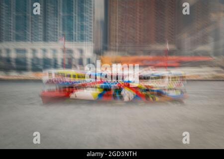 Trattamento di sfocatura zoom della 'Night Star', una delle flotte Star Ferry, passando per gli alti blocchi di appartamenti di Union Square, West Kowloon Foto Stock